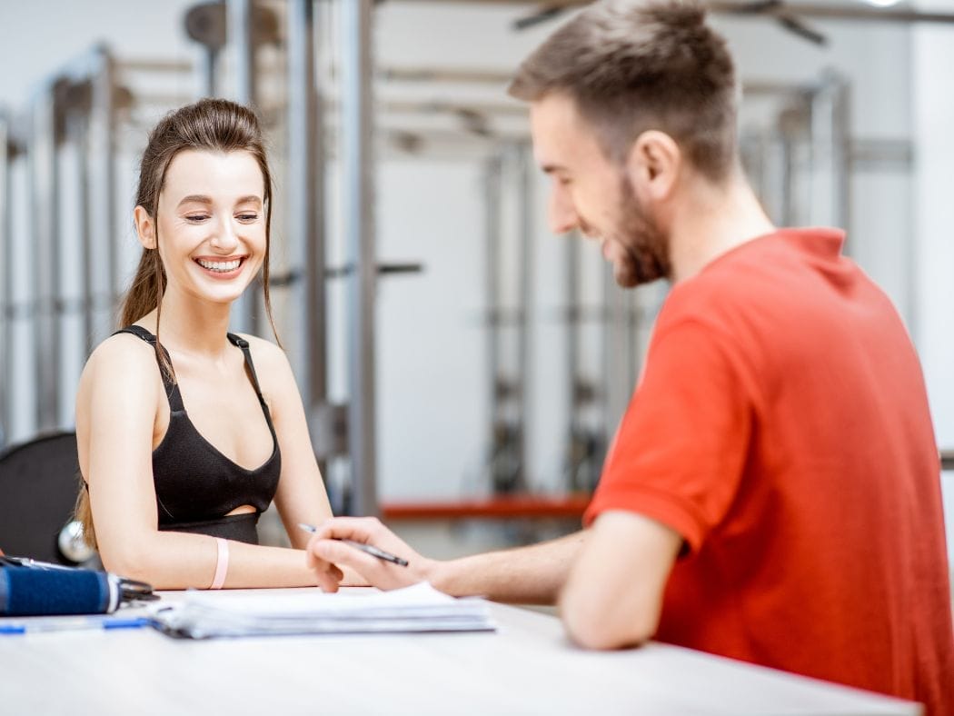 New gym member in a consultation with a trainer, discussing goals and fitness plans—highlighting why a No Sweat Intro is better than a gym free trial.