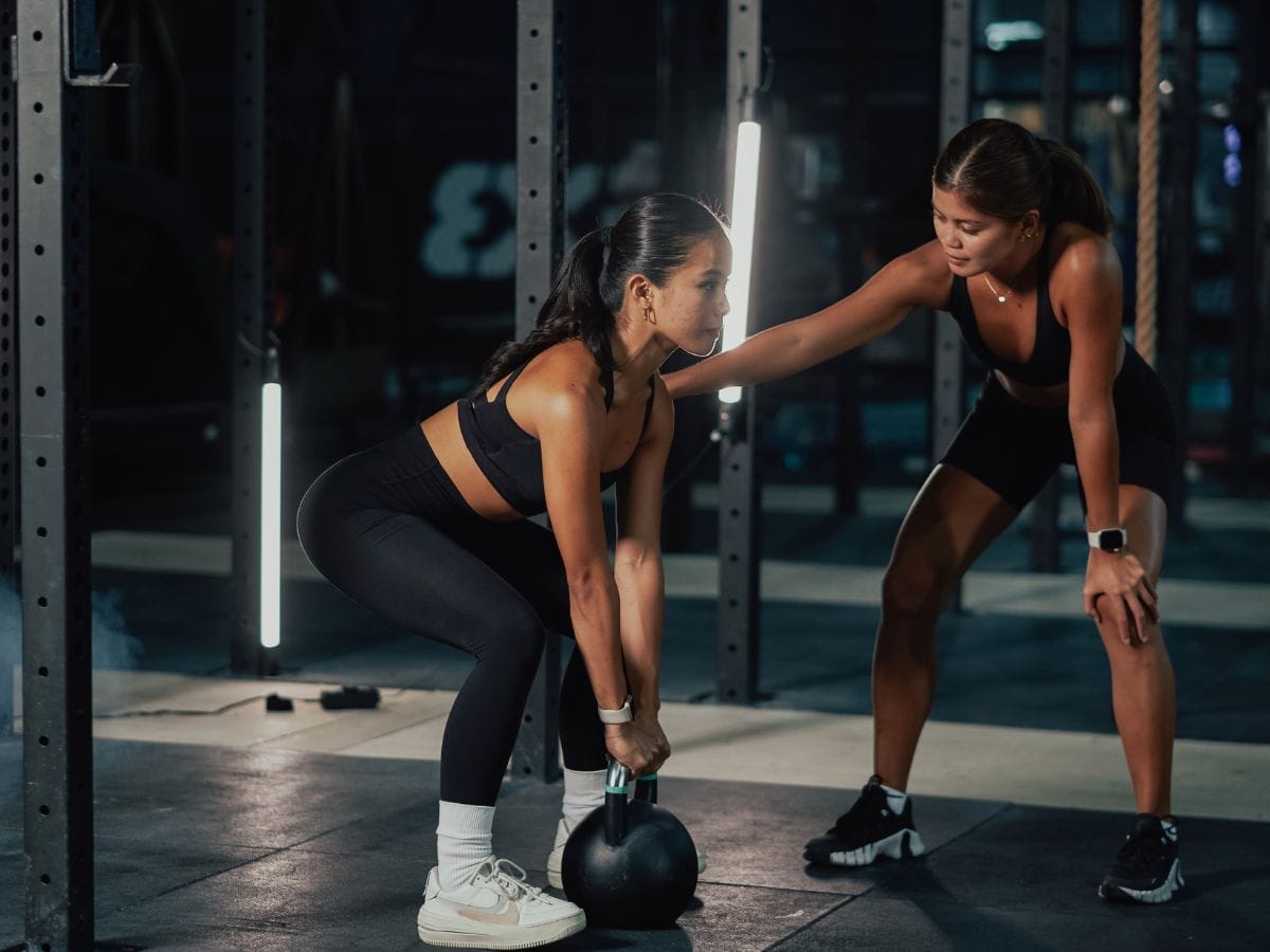Coach guiding member through strength training at FIIT Project gym in Norwood
