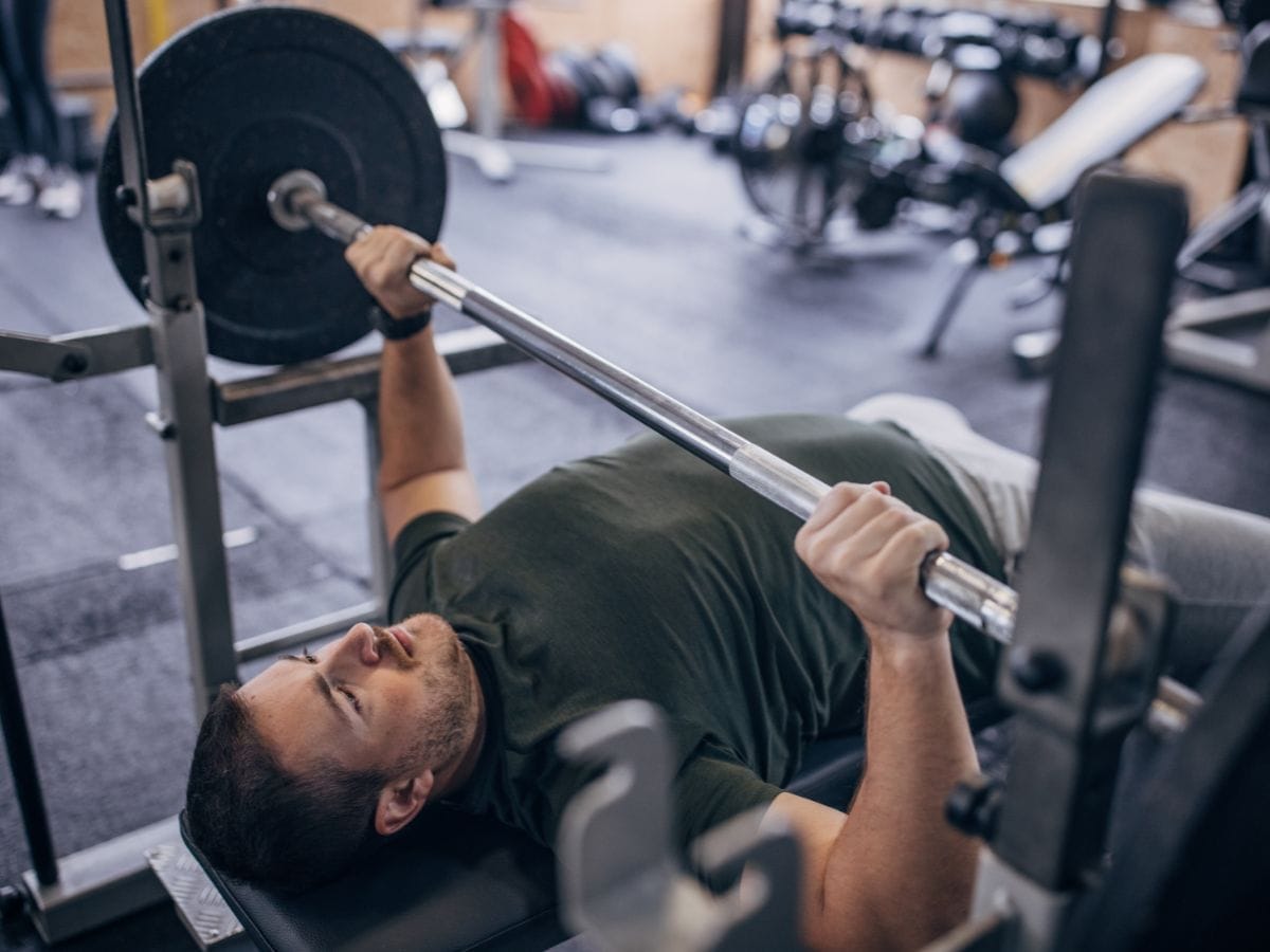 Middle-aged man performing a bench press to demonstrate strength standards for men over 40